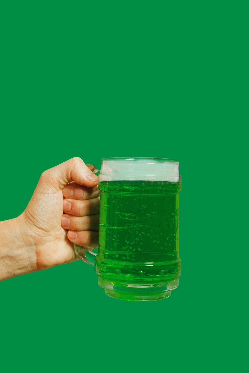 person holding clear glass mug with green liquid